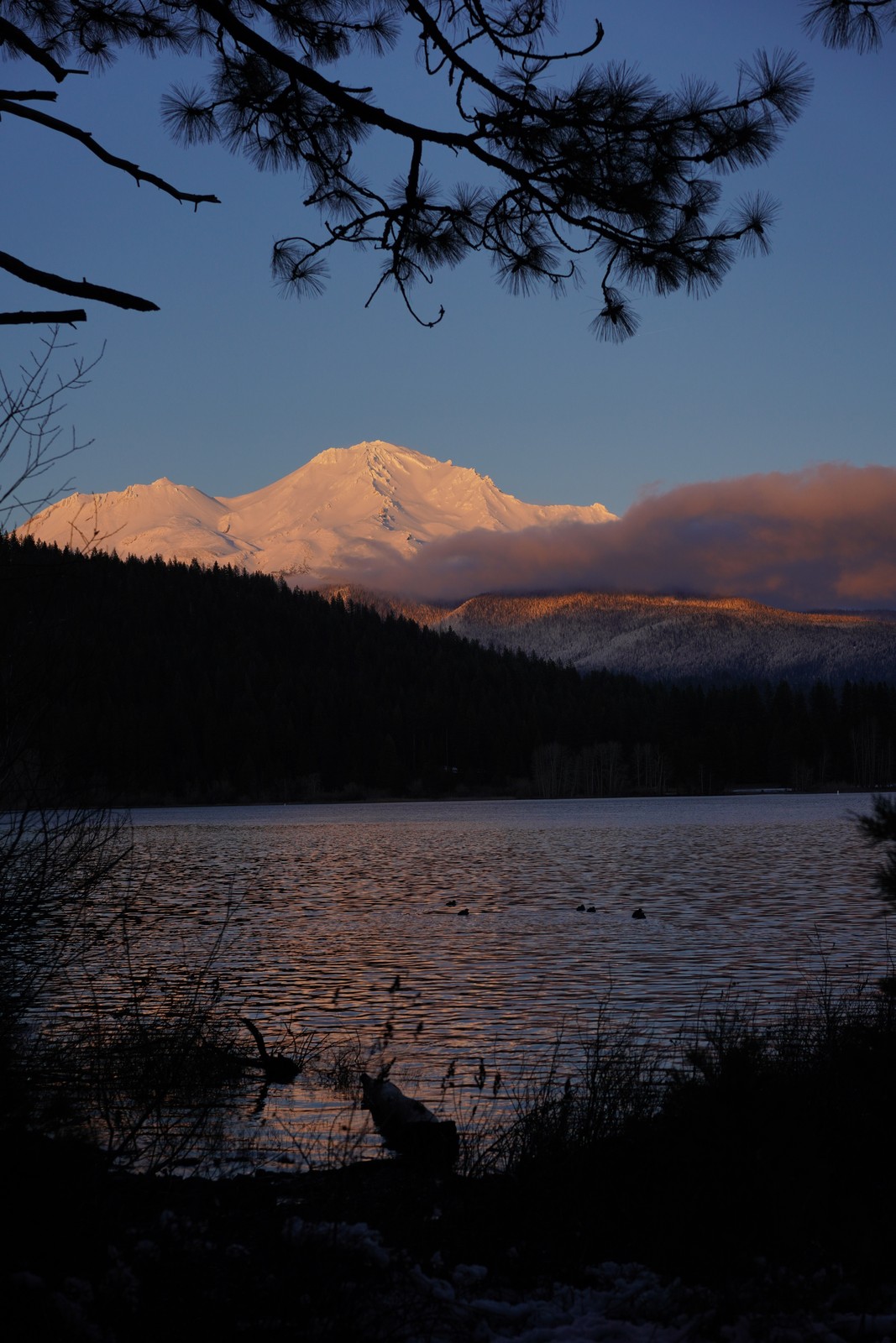 Sunlit mountain peaks above a quiet lake.